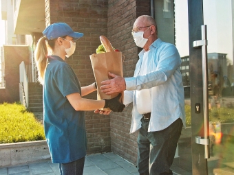 Delivery of food in quarantine. Senior man in protective mask customer receiving food bag.