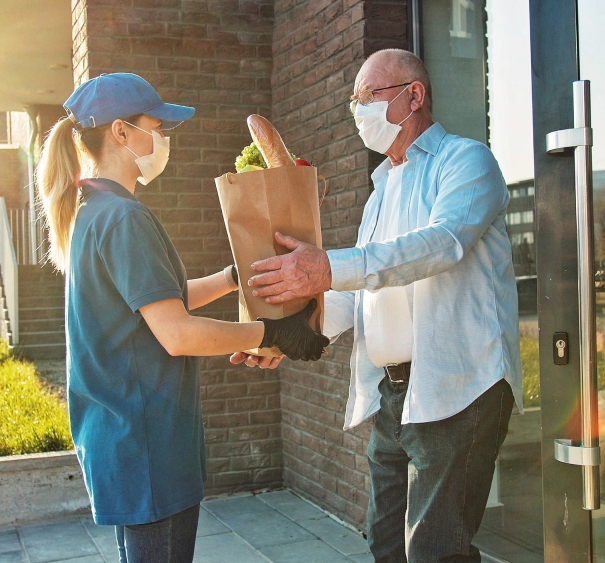 Delivery of food in quarantine. Senior man in protective mask customer receiving food bag.