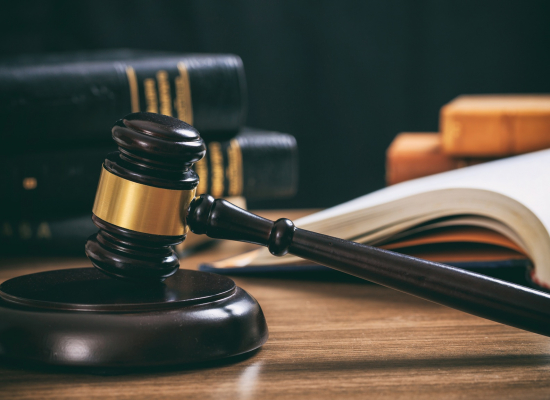 Judge gavel on a wooden desk, law books background