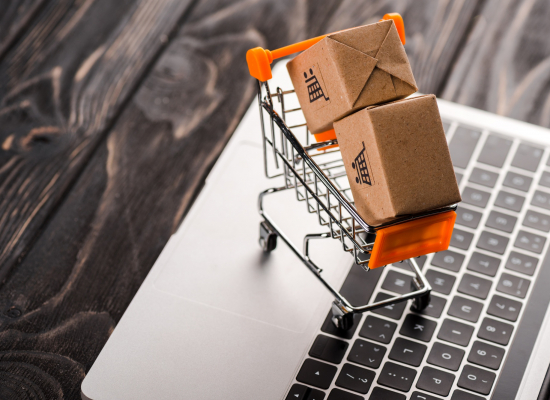 toy boxes in small shopping cart on laptop, e-commerce concept